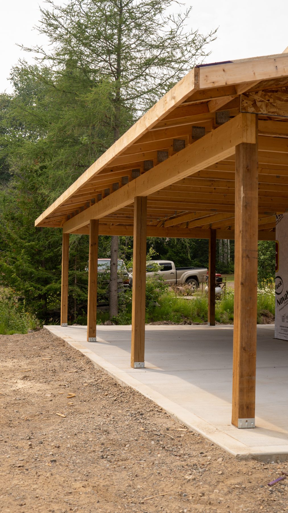 Covered timber-frame structure under construction, with exposed posts and beams